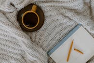 A relaxing flat lay of tea, planner, and warm knitted blanket for planning days.
